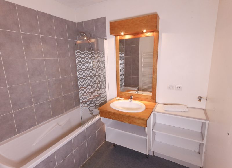 Salle de bain avec baignade et lavabo. miroir cadre bois