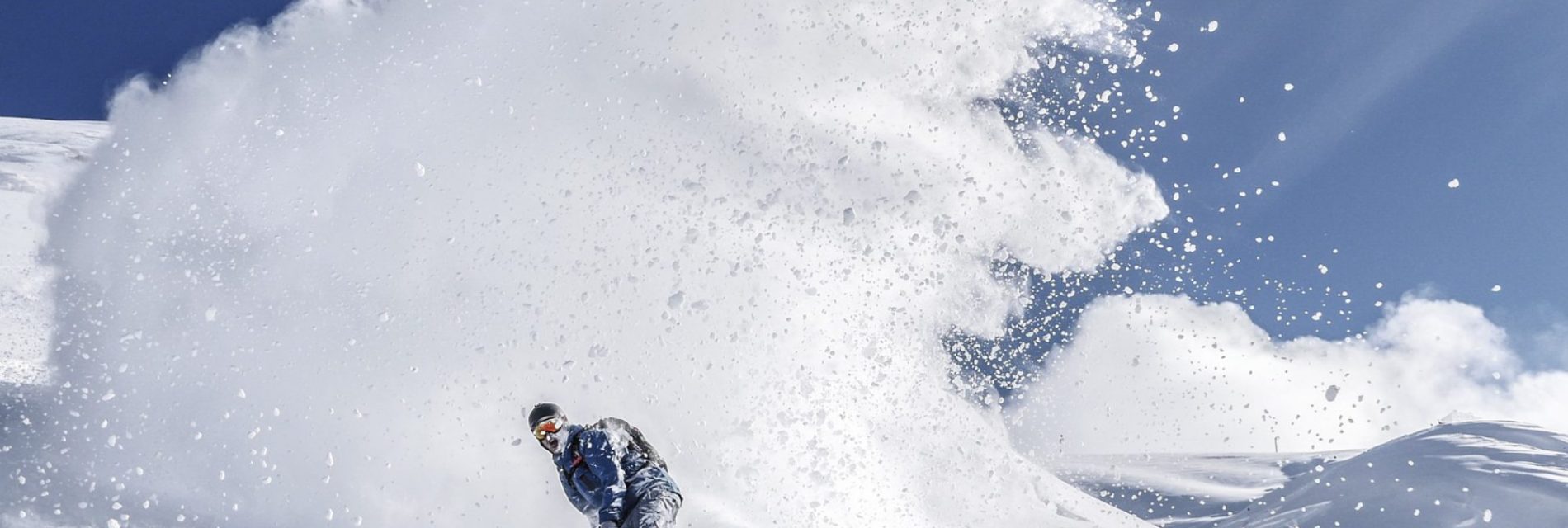 Vacances à la montagne. Homme en snowboard sur les pistes. Grande tracé de neige derrière lui.